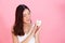 Portrait of young Asian woman holding a piggy bank, happy and excited over own saving over vivid pink background.