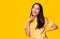 Portrait young asian woman look at copy space Beautiful girl wear yellow T shirt with yellow background at studio Pretty asia