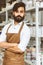 Portrait of a young attractive businessman craftsman with a beard and mustache in his workshop.. Posing arms crossed