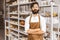 Portrait of a young attractive businessman craftsman with a beard and mustache in his workshop.. Posing arms crossed