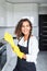 Portrait of young attractive caucasian brunette housewife at kitchen wearing the yellow rubber gloves