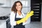 Portrait of young attractive caucasian brunette housewife at kitchen wearing the yellow rubber gloves