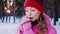 Portrait of a young attractive caucasian woman in a winter forest. Warms hands in pink gloves