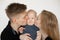 Portrait of young attractive family in dark clothes with plump cherubic baby infant toddler stand on white background.