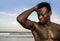 Portrait of young attractive and fit black afro American man with strong muscular body posing cool model attitude on the beach