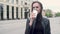 Portrait of a young attractive girl in a black leather jacket. standing in the cold wind and drinking coffee from a paper Cup. cit