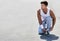 Portrait of young attractive man wearing sports wear tying his rubber shoes in park