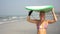 Portrait of a young attractive surfer woman on the beach with a surfboard