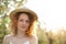 Portrait young attractive woman with curly hair in a stylish wicker hat in a green garden