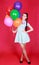 Portrait of a young attractive woman holding bunch of many bright balloons