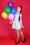 Portrait of a young attractive woman holding bunch of many bright balloons