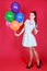 Portrait of a young attractive woman holding bunch of many bright balloons