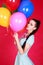 Portrait of a young attractive woman holding bunch of many bright balloons