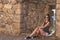 Portrait young attractive woman with sunglasses look at camera serious sitting over isolated stone wall background