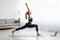 Portrait of young balanced woman in sportswear doing yoga pose on mat at home with notebook beside