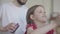 Portrait young bearded father brushing the hair of his little girl while the child combing her toy sitting on floor on