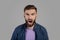 Portrait of young bearded guy shouting furiously, expressing his anger over grey studio background. Negative emotions