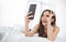 Portrait of young beautiful asian woman relax using smart phone selfie live in her bedroom.