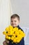 Portrait of a young, beautiful boy. Holds a huge armful of fresh yellow tulips. The concept of spring and holiday, March 8,
