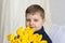 Portrait of a young, beautiful boy. Holds a huge armful of fresh yellow tulips. The concept of spring and holiday, March 8,