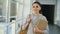 Portrait of young beautiful caucasian confident female student standing in white glassy corridor smiling positively