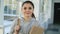 Portrait of young beautiful caucasian confident female student standing in white glassy corridor smiling positively