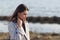 Portrait of a young beautiful charismatic brunette girl in a coat on the coast of the sea