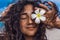 Portrait of young and beautiful cheerful woman with frangipani flower on the beach