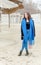 Portrait of young beautiful and cute girl in black coat and blue scarf outdoors on the cold weather with reed sunshades in the bac