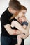 Portrait of young beautiful family in dark clothes with plump cherubic baby infant toddler standing on white background.