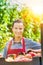 Portrait of young beautiful farmer leaning on tomatoes in crates at greenhouse with yellow lens flare