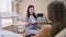 Portrait of young beautiful female dentist talking in slow motion with teenage patient sitting in chair indoors