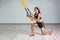 Portrait of young beautiful fit woman in sportswear doing squat exercise on one knee with fitness straps in the gym. Functional