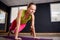 Portrait of the young beautiful fitness woman doing plank position indoors at the gym on the violet yoga mat.