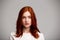 Portrait of young beautiful ginger girl over gray background.