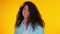 Portrait of young beautiful girl corrects her curls on yellow background. Trendy cute woman smiling to camera. Studio