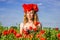 Portrait of a young beautiful girl in a poppy field with a wreath of poppies on her head on a hot summer sunny day