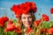 Portrait of a young beautiful girl in a poppy field with a wreath of poppies on her head on a hot summer sunny day