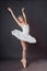 Portrait of young beautiful graceful caucasian ballerina practice ballet positions in tutu skirt of white swan from Swan Lake.