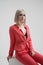 Portrait of a young beautiful informal blonde girl with dyed hair. Red jacket suit on the naked body. Studio photoshoot