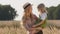 Portrait young beautiful mother blonde woman in straw hat stands in wheat field holding little daughter girl smiling