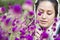 A portrait of a young beautiful muslim woman in a white shawl in front of purple flowers