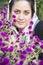 A portrait of a young beautiful muslim woman in a white shawl in front of purple flowers vertical shot