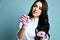 Portrait of young beautiful sexy brunette woman doctor or nurse in white costume and pink gloves holding accessories