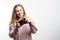 Portrait of a young beautiful smiling blonde girl wearing pale pink knitted sweater with a vintage camera in her hands