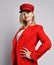 Portrait of young beautiful smiling woman in stylish elegant deep red official suit, red cap and massive earings touching peak