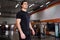 Portrait of young beautiful sportsman in the black sportwear while standing with in gym