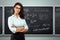 Portrait of a young beautiful teacher on the background of the school blackboard. Teacher`s Day Knowledge Day back to school stud