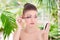 Portrait of young beautiful woman applying mascara on her eyelashes over summer background