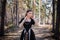 Portrait of a young, beautiful woman in a black medieval dress standing in a pine forest. Attractive girl in a gothic dress.